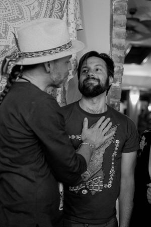 Two people having an intimate conversation against a patterned backdrop.