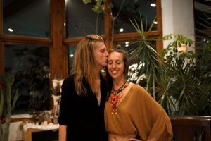 Two people share a warm moment together at a cozy indoor venue with plants in the background.