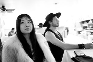Black and white photo of two people at an event with one wearing a fur coat.