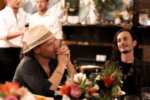 Casual gathering with straw hat wearing attendee at dinner table with floral centerpiece.