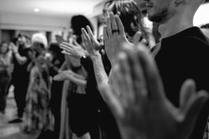 Black and white image of raised hands during what appears to be a worship or prayer session.