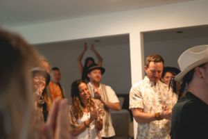 Group of audience members clapping and enjoying an intimate indoor performance.