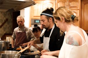 People working together in a kitchen preparing food with striped aprons.