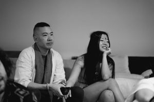 Candid black and white photo of people relaxing on a couch during a social gathering.
