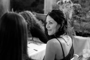 A candid black and white photo captures a person smiling during a social gathering.
