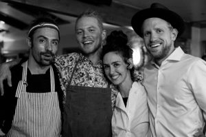 Restaurant staff members pose together in a black and white photo wearing aprons and casual attire.