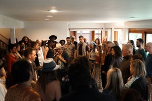 Large group gathers in bright indoor space for a community performance event.
