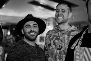 Two friends smile together during an indoor social gathering.