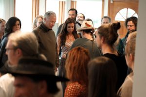 Crowded indoor gathering with people mingling in hallway.