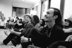 Black and white image of attendees enjoying a cozy indoor performance.