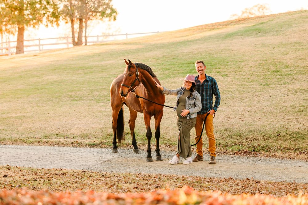 A horse and rider walk along a scenic rural path during golden hour at sunset as shadows stretch across the landscape.