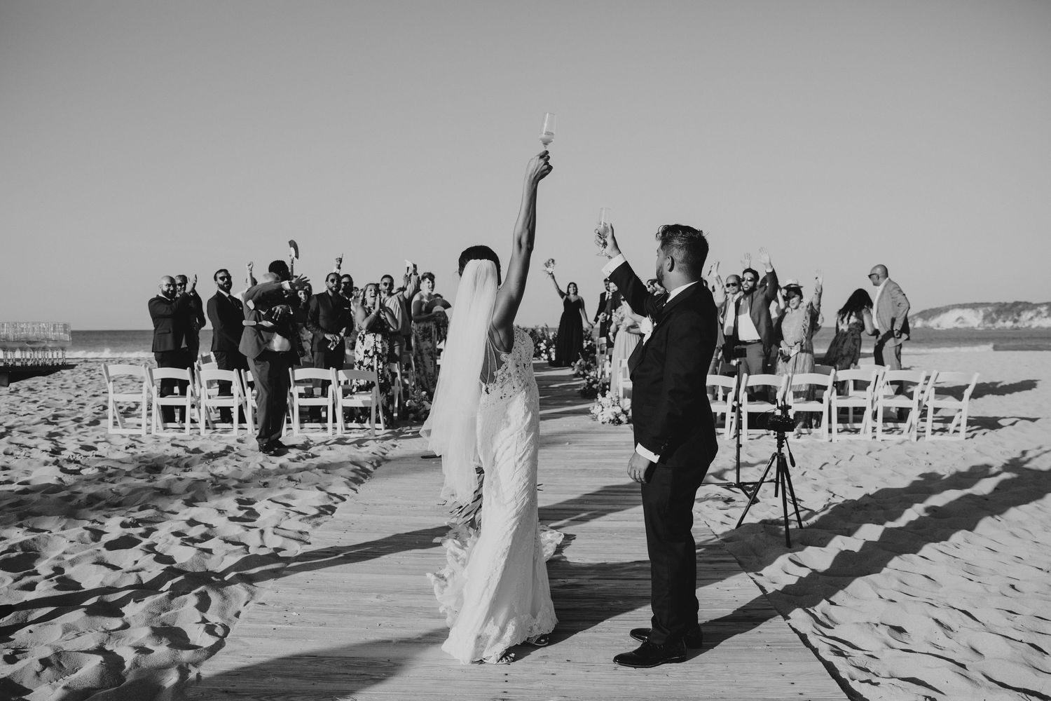 Black and white photo of a beach wedding ceremony with guests seated in rows.