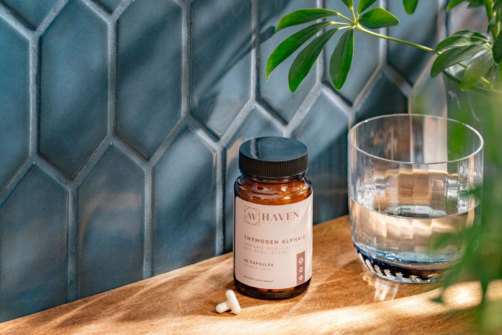 A bottle of Botaniva supplements sits beside a glass of water on a wooden surface with teal hexagonal tiles in background.