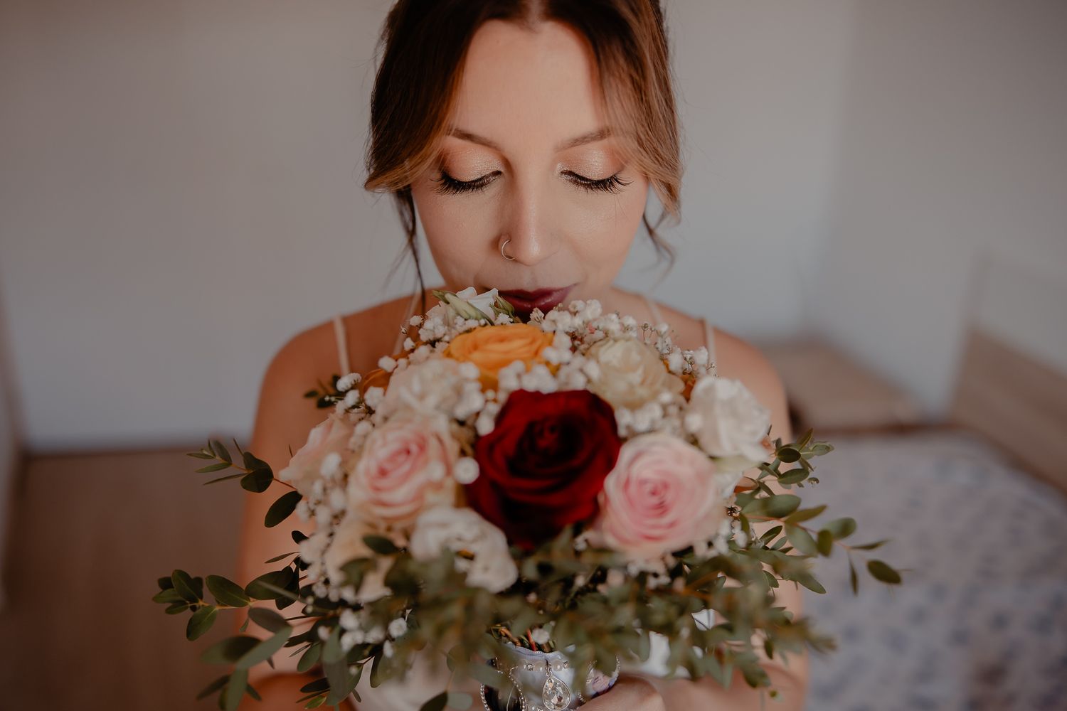 A delicate bouquet of pink and white roses with greenery held against a light background.