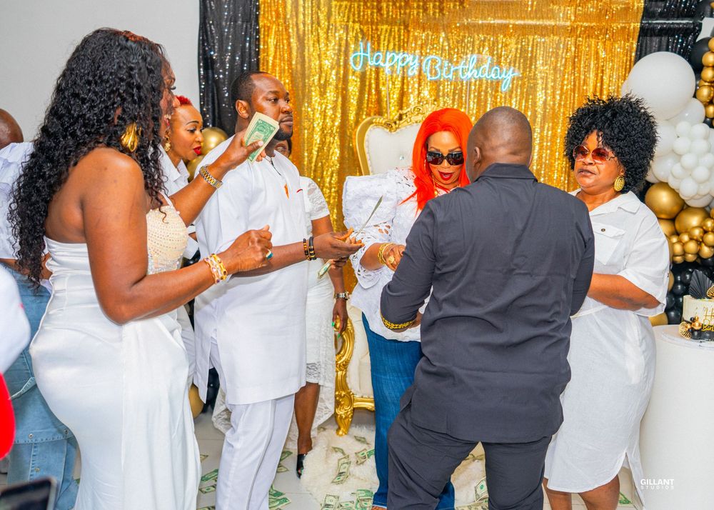Group of party guests in coordinated white outfits dancing and celebrating at an event.