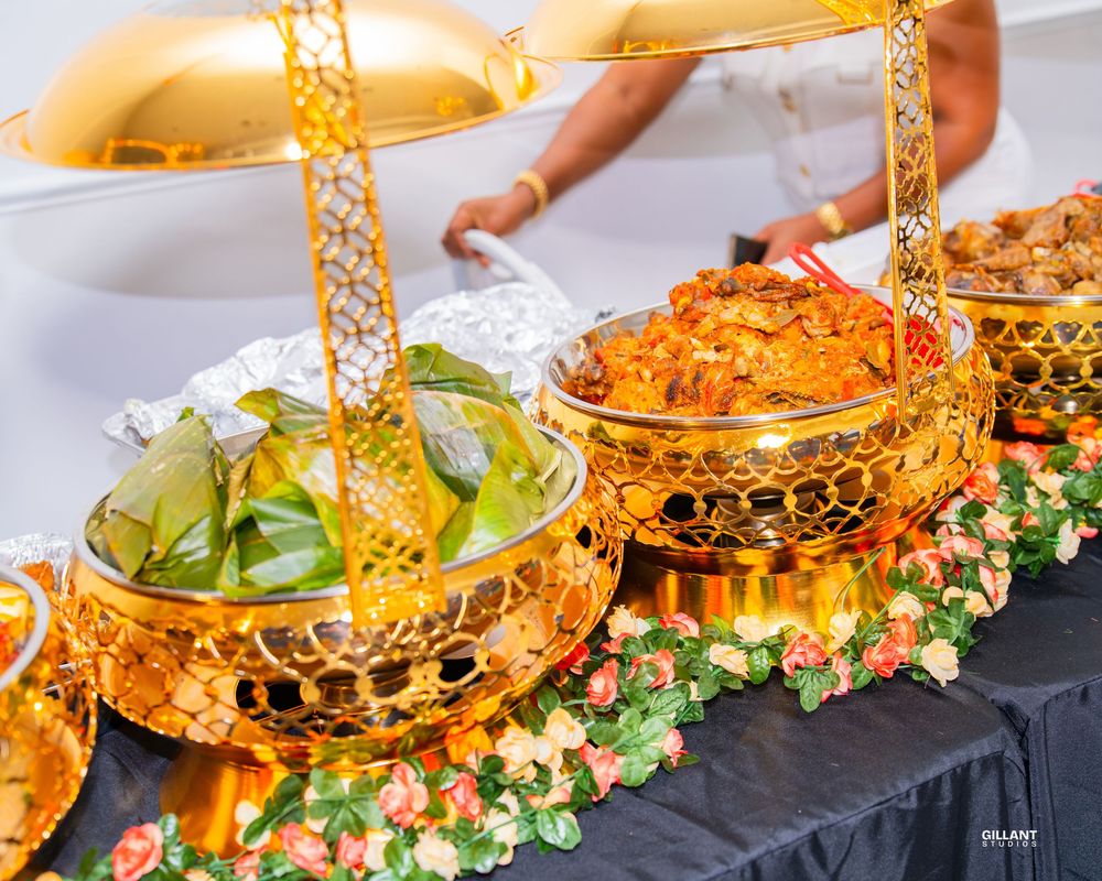 Ornate golden serving dishes with floral decorations at an elegant buffet setup.