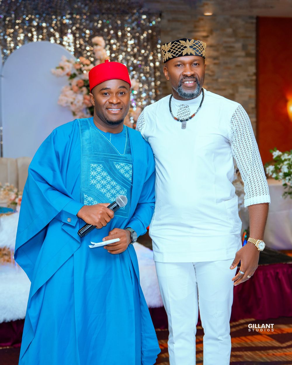 Traditional wedding guests in bright blue and white attire pose together at a decorated venue.