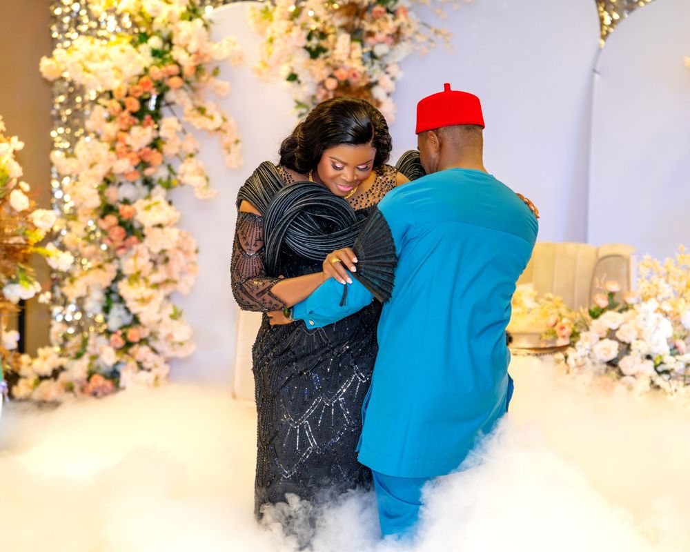 Couple dancing at an elegant event with floral arch decorations in the background.