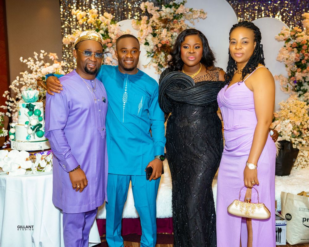 Group photo of four people in formal attire at an event with floral decorations.