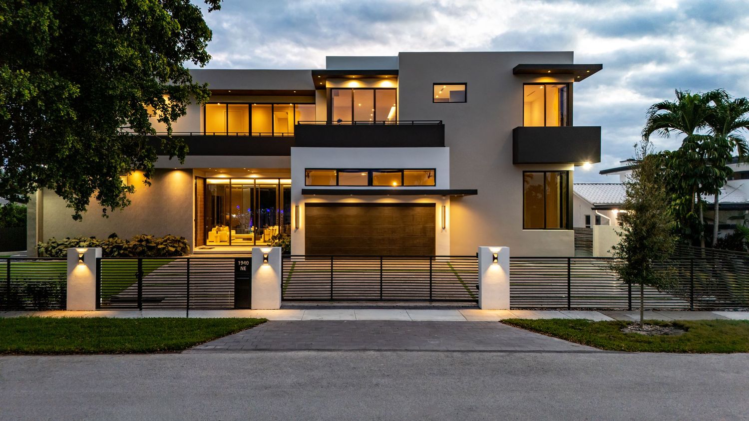 Modern luxury home exterior with clean lines and large windows photographed at twilight.