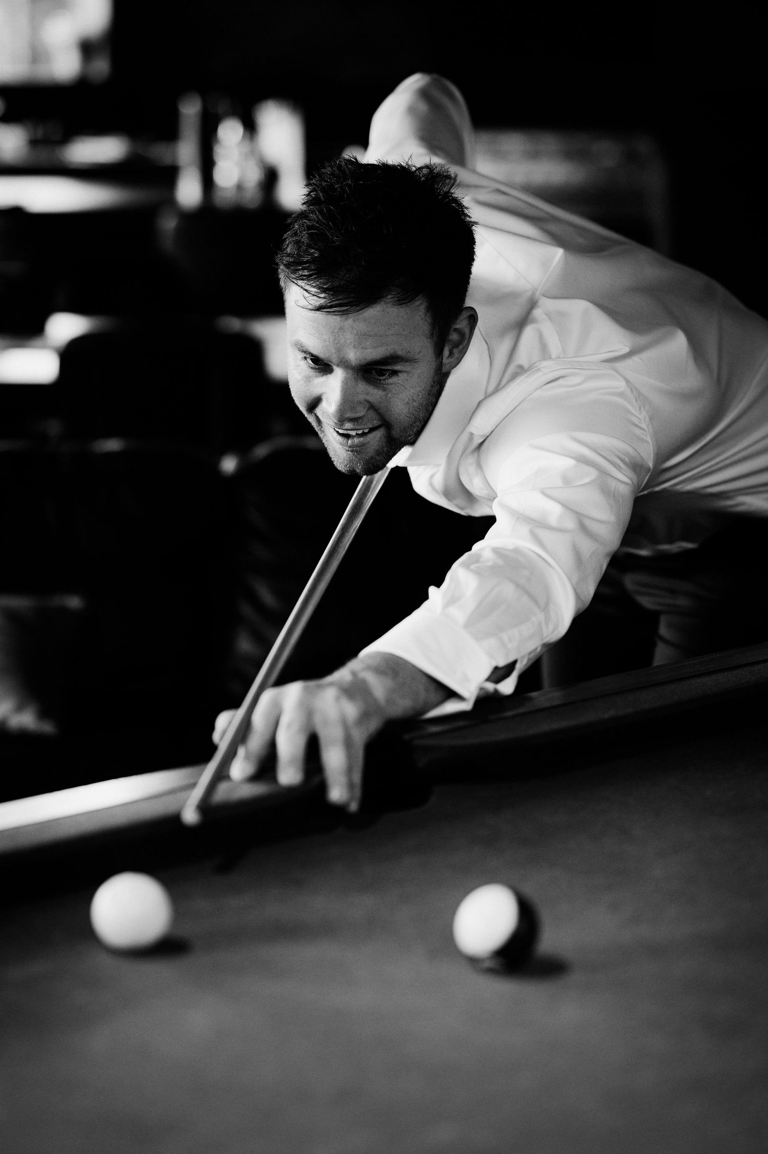 Black and white sequence showing a player lining up and executing a billiards shot on a pool table.