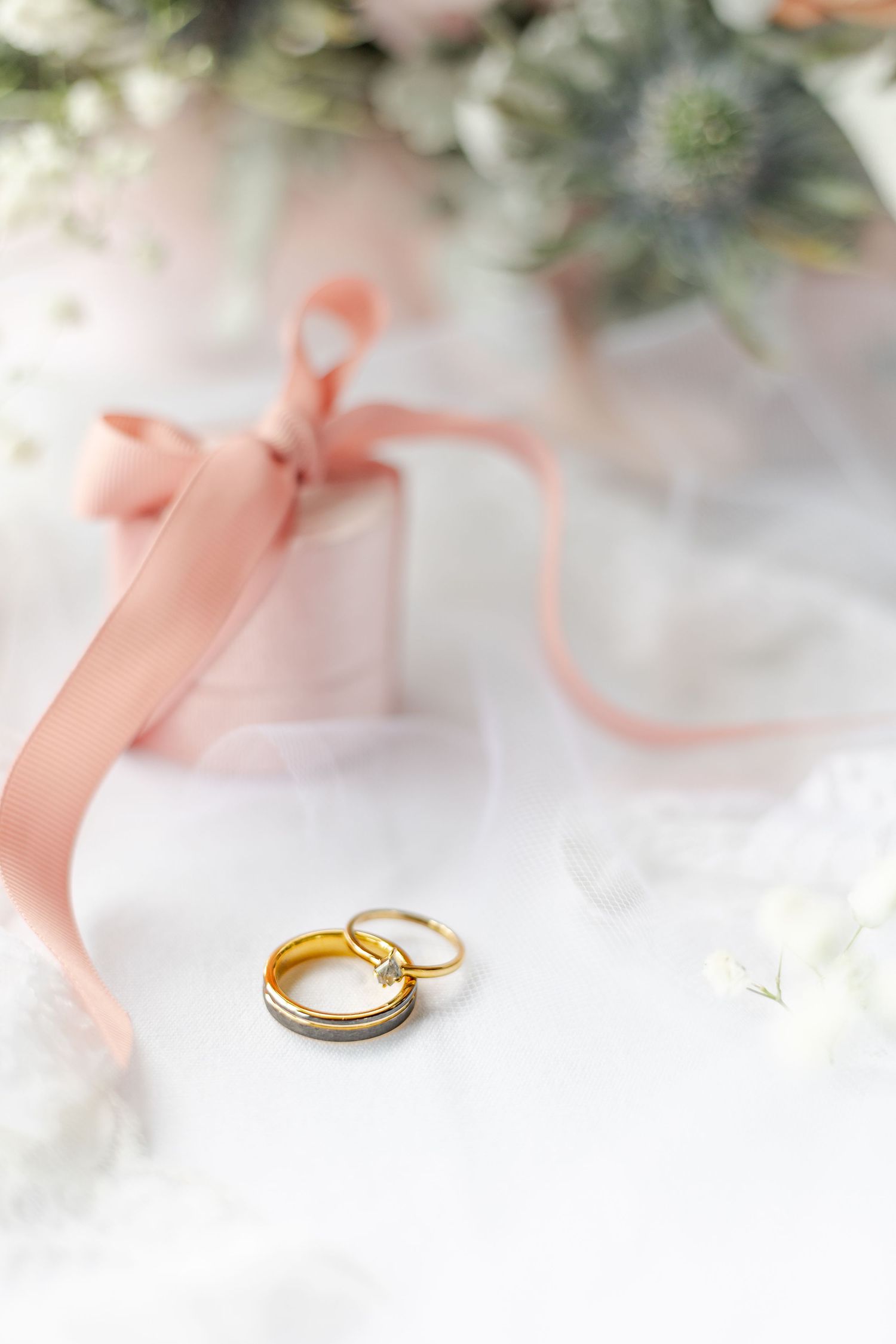 Faded pastel pink hues of floral displays with blush coloured ring box and golden wedding rings