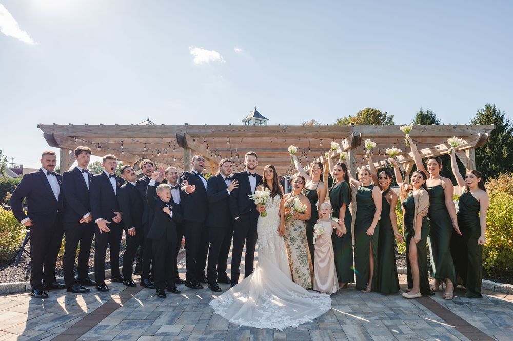 Wedding party members pose together outdoors in formal attire during golden hour at t The Barn at Villa.