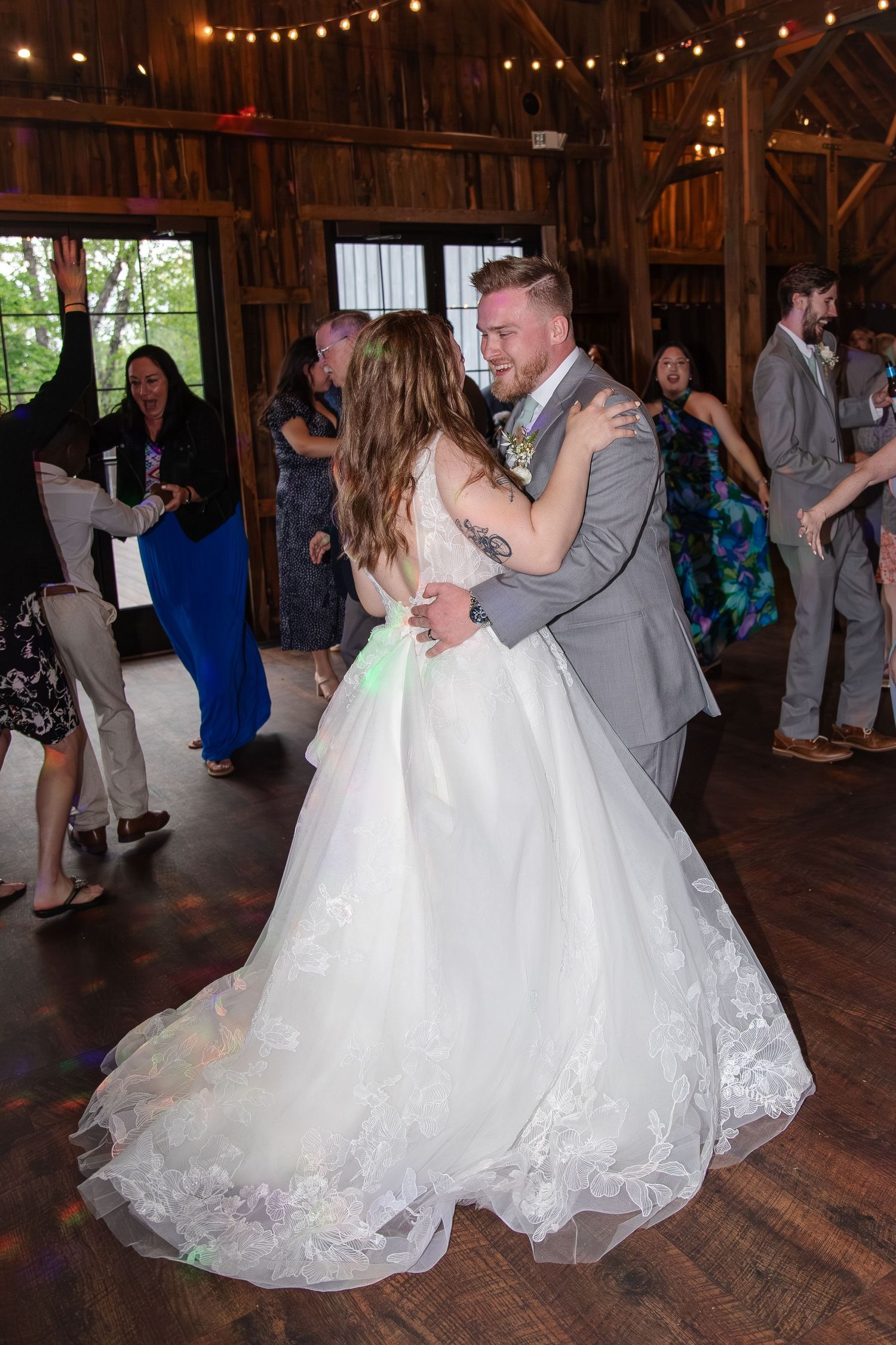 Couples dancing at a wedding reception in a rustic barn venue with string lights overhead in Burlington, Wisconsin.