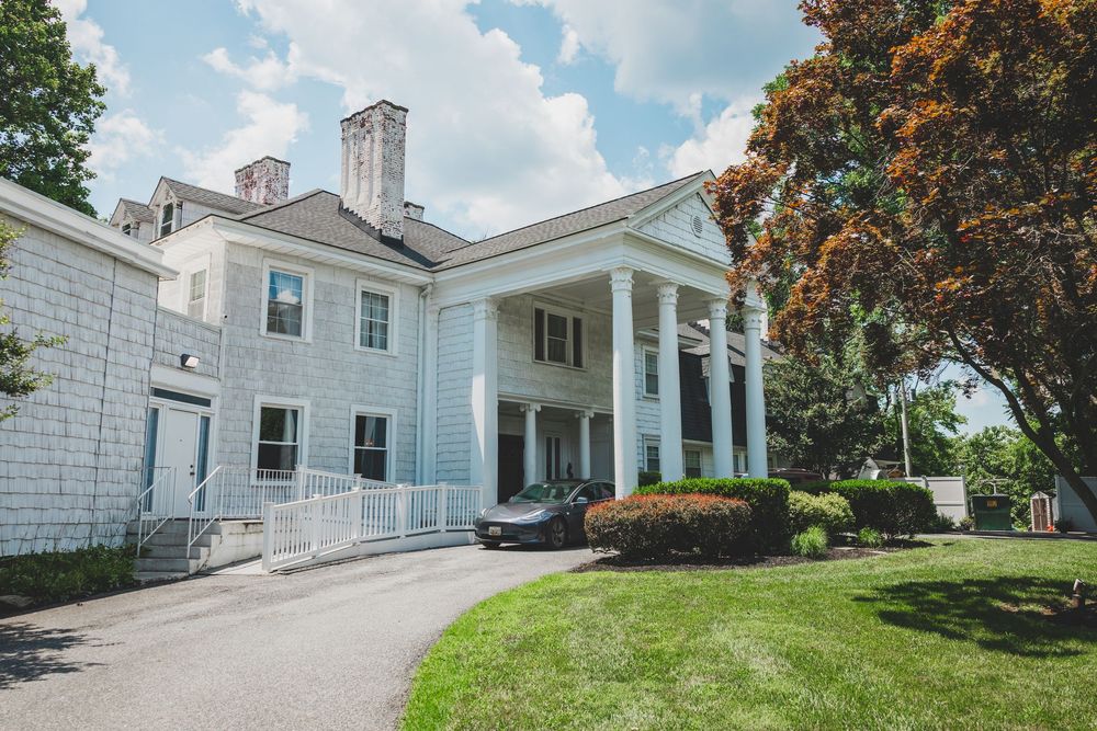 Overhills mansion with columns and landscaping viewed from multiple angles on a sunny summer day.