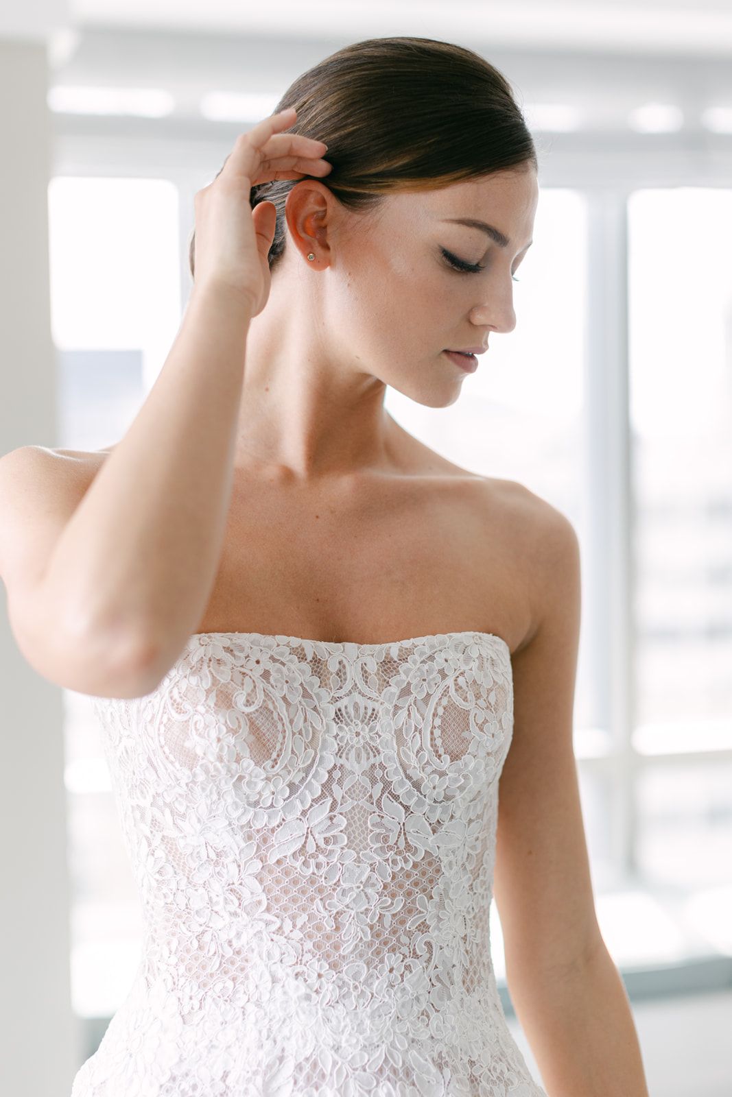 Elegant strapless wedding gown with delicate floral lace details and fitted bodice in bright natural lighting.