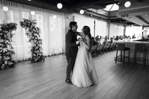 Wedding celebration with guests dancing in a spacious venue with large windows.