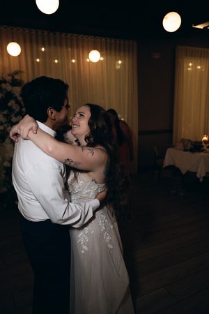 Couple dancing romantically under string lights at an evening reception.