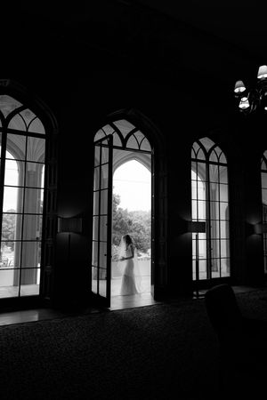 Gothic arched windows create dramatic silhouettes in a dark corridor.