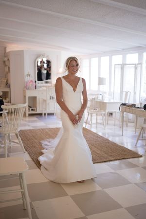 White wedding dress flows gracefully across a checkered floor in a bright, modern room.