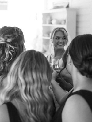 Wedding party members gather in a bright indoor space with soft lighting.
