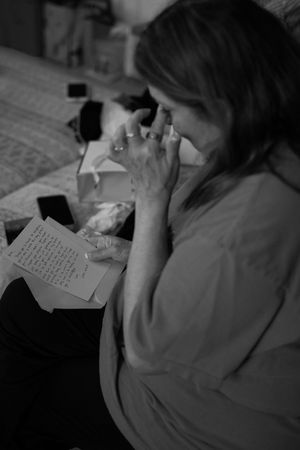 Person writing in a notebook shown in intimate black and white photography.