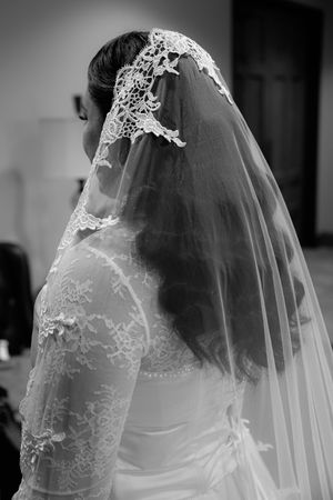 A black and white photograph showing an elegant lace wedding veil with delicate embroidery details.
