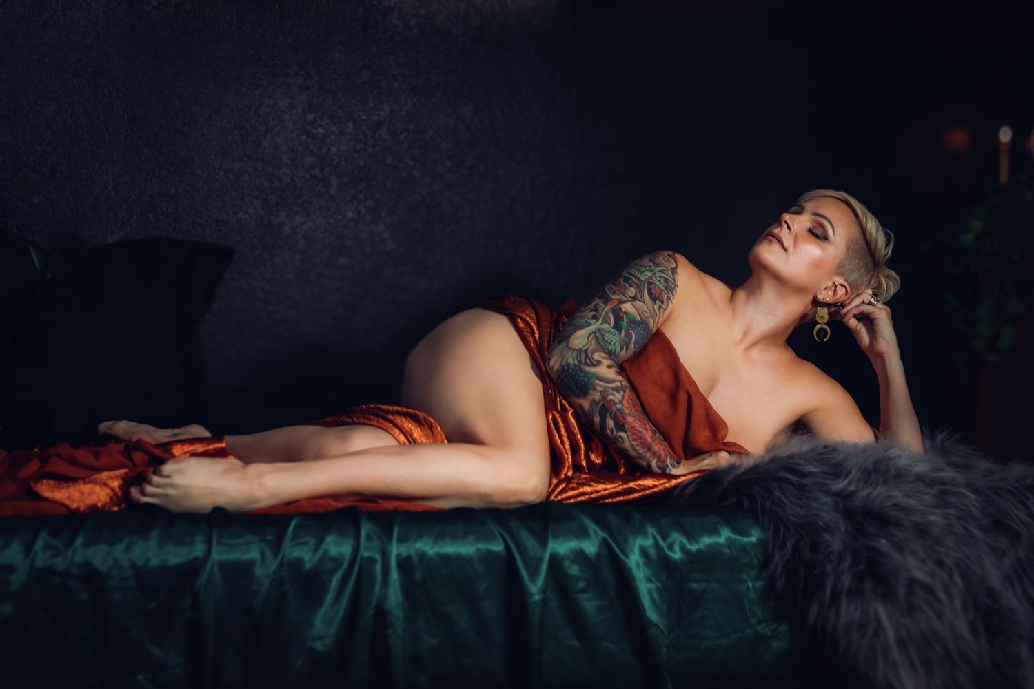 Client lounging in rich orange fabric during an artistic Fort Worth boudoir shoot focused on confidence and self-expression.