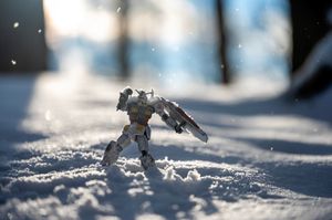 Small gundam figure standing in pristine snow with bokeh effect in background.