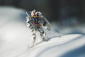 White Gundam robot figure standing in snowy landscape.
