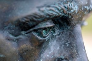 Extreme close-up detail of a bronze statue's eye showing weathered patina and texture.