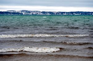 Waves rolling onto shore with distant snow visible along the coastline.