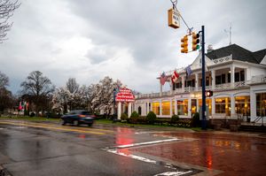 Rainy street scene of a small town shopping district with traffic lights and reflective wet pavement.