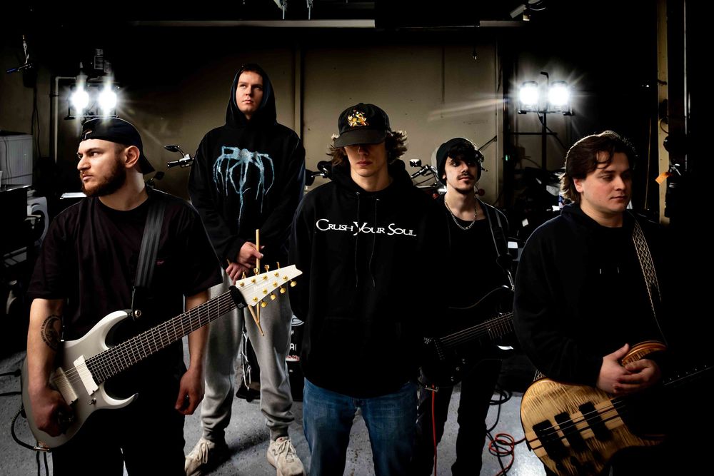 Musicians with instruments in a dark studio setting during band practice.