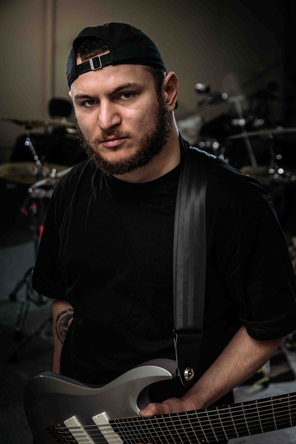 A bass player performs in a dark studio setting wearing black clothing.