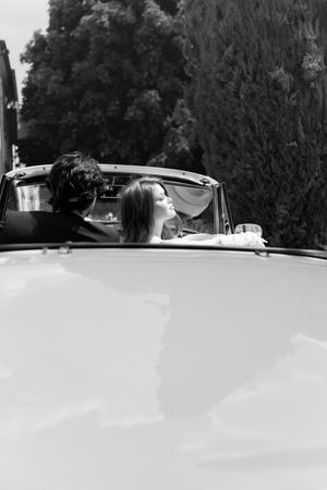 A black and white panoramic photo showing a sleek vintage convertible car parked in front of trees.