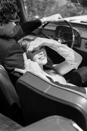 A person sleeping during travel in the passenger seat of a vehicle wearing a pale colored outfit.