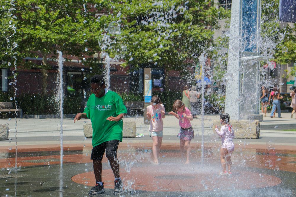 People enjoy cooling off in an urban water fountain plaza.