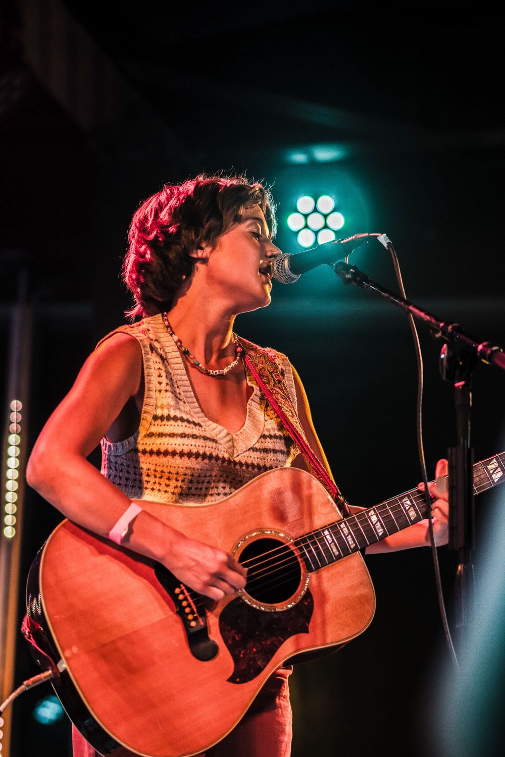 Musician performs on acoustic guitar under blue stage lighting at live concert venue.