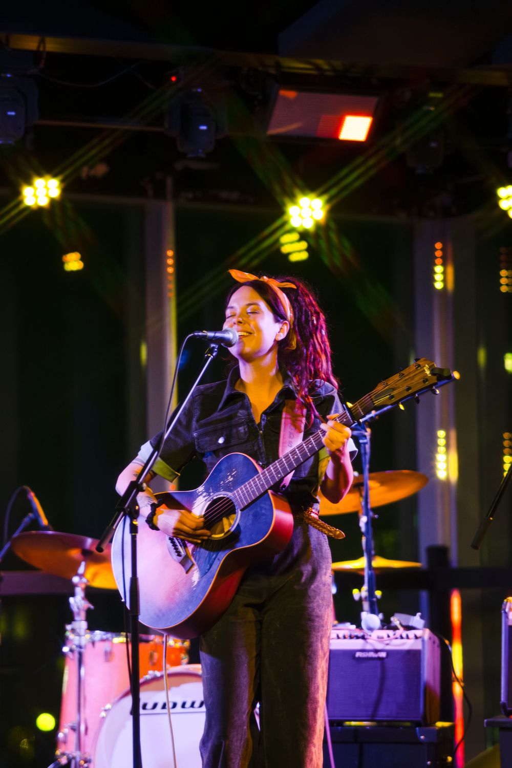 Stage performance featuring acoustic guitar player with dramatic concert lighting.